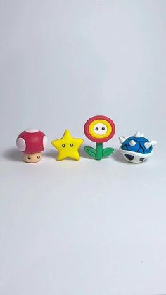 three small toys are sitting next to each other on a white surface, one has a flower and the other has a fish