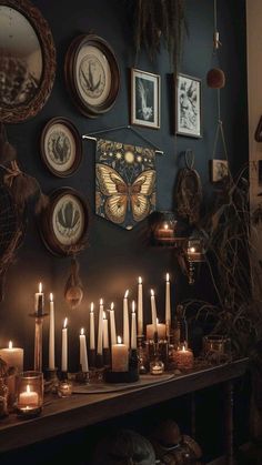 many candles are lit on a table in front of pictures and other things hanging on the wall