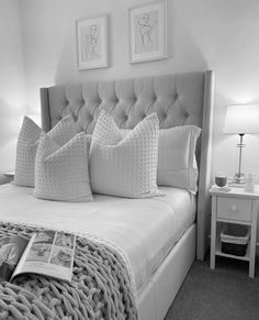 black and white photograph of a bed with two framed pictures on the wall above it