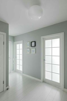 an empty room with white floors and two doors on either side of the door are three framed pictures