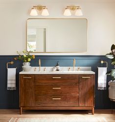 a bathroom with two sinks and a mirror on the wall next to a potted plant