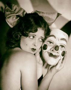 a woman is holding a mask in front of her face while posing for a black and white photo