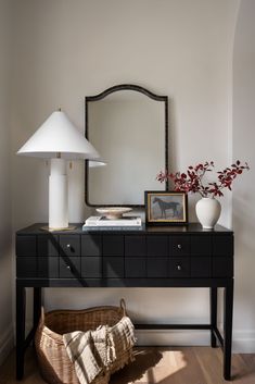 a table with a mirror, lamp and vase on it