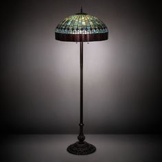 a lamp that is sitting on top of a table with a black base and green glass shade