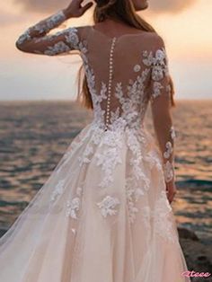 a woman standing on top of a beach next to the ocean wearing a wedding dress