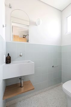 a bathroom with a toilet, sink and mirror in it's corner area next to a window