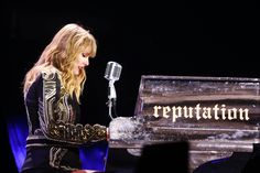 a woman standing in front of a piano with a microphone next to her on stage