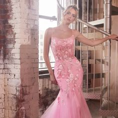 a beautiful woman in a pink dress posing for a photo with her hand on the rail