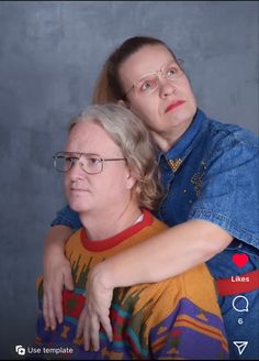 two women are hugging each other in front of a gray background and the woman is wearing glasses