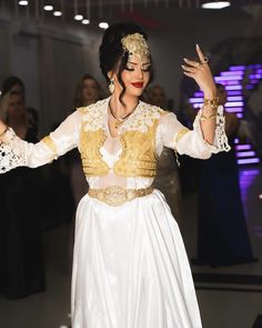 a woman in a white and gold dress dancing