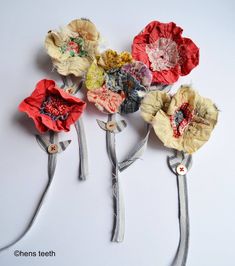 four different colored flowers with ribbons attached to each flower headband, on a white surface