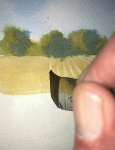 a hand is holding a paintbrush over a painting