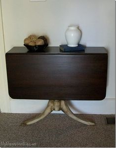 a table with two vases on top of it next to a white wall and carpeted floor