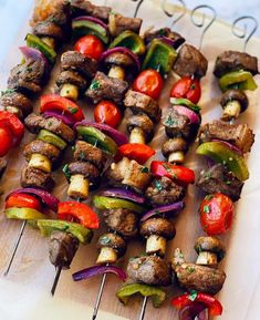 several skewers of meat and vegetables on a cutting board