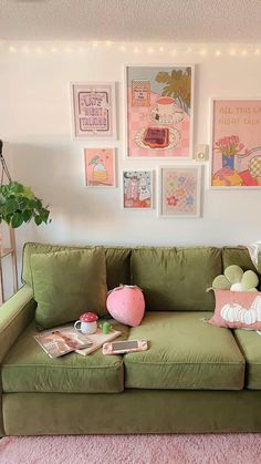 a green couch with pink pillows and pictures on the wall