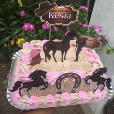 a birthday cake with horses on it in front of some pink and purple flowers,