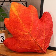 an orange leaf sitting on top of a wooden table next to a clock and calendar