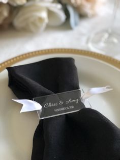 a place setting with black napkins and white flowers