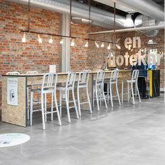 an empty restaurant with white chairs and brick wall in the background, there is no one sitting at the bar