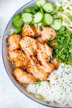 a bowl filled with rice, cucumbers and salmon