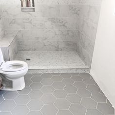 a white toilet sitting inside of a bathroom next to a walk in shower stall with tiled walls