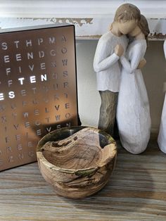 a wooden bowl sitting on top of a table next to a couple figurines