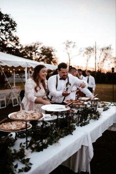 a man and woman standing at a table with plates of food in front of them