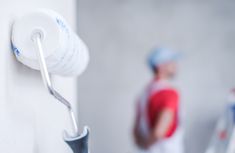 a man standing next to a wall holding a pair of scissors