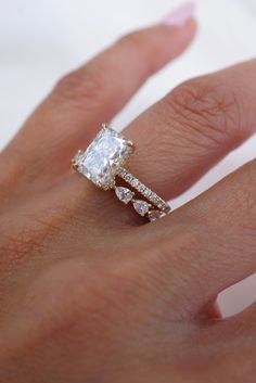 a woman's hand with a diamond ring on top of her finger and an engagement band