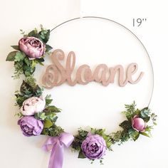 a wreath with flowers and the word sloane spelled in cursive wood letters