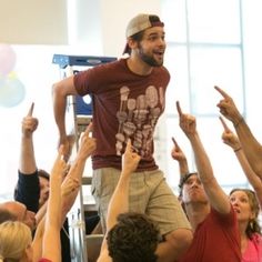 a man standing on top of a group of people with their hands in the air