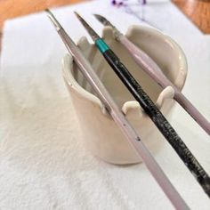 some paint brushes are in a cup on a table