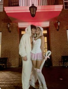 two people dressed in bunny costumes standing next to each other near a red and white building