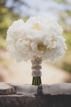 a bouquet of white flowers sitting on top of a brick wall