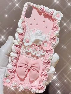 a pink phone case with a bow and pearls on the back, in front of a shiny background