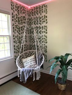 a white hanging chair next to a potted plant