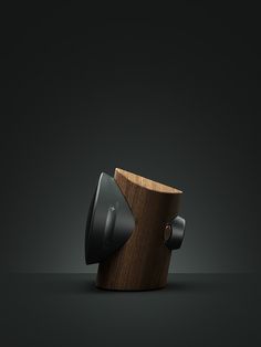 an unusual wooden object with two black knobs on it's sides and a dark background