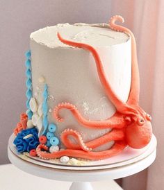 an octopus cake is decorated with white frosting and orange icing on a pedestal