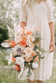 a woman holding a bouquet of flowers in her hand and wearing a white lace dress