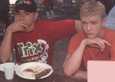 two young men sitting at a table with food