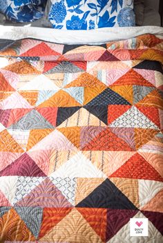 a bed with a colorful quilt on it and pillows in the back drop down position