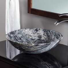 a black and white bowl sink sitting on top of a counter next to a mirror