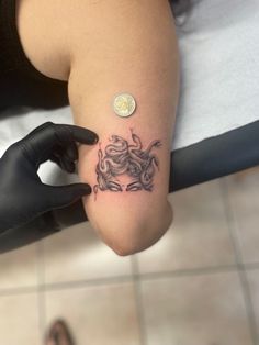 a person with a tattoo on their arm holding a small coin in the other hand