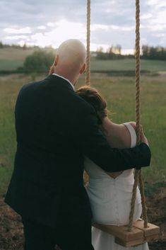 a bride and groom are sitting on a swing