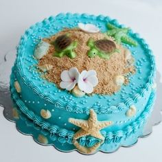 a blue cake with sand and flowers on it