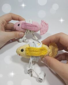 two crocheted fish ornaments being held by someone's hands on a white surface