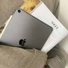 an apple ipad in someone's lap with some books and magazines on their lap