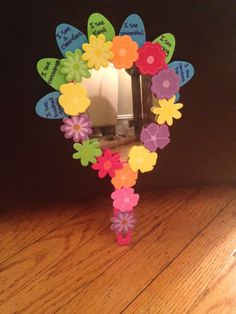 a mirror that has flowers on it and is sitting on a wooden table next to a wall