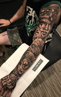 a man's arm with tattoos on it and some people sitting in the background