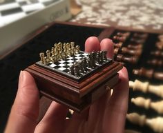 a hand holding a wooden chess board with pieces on it